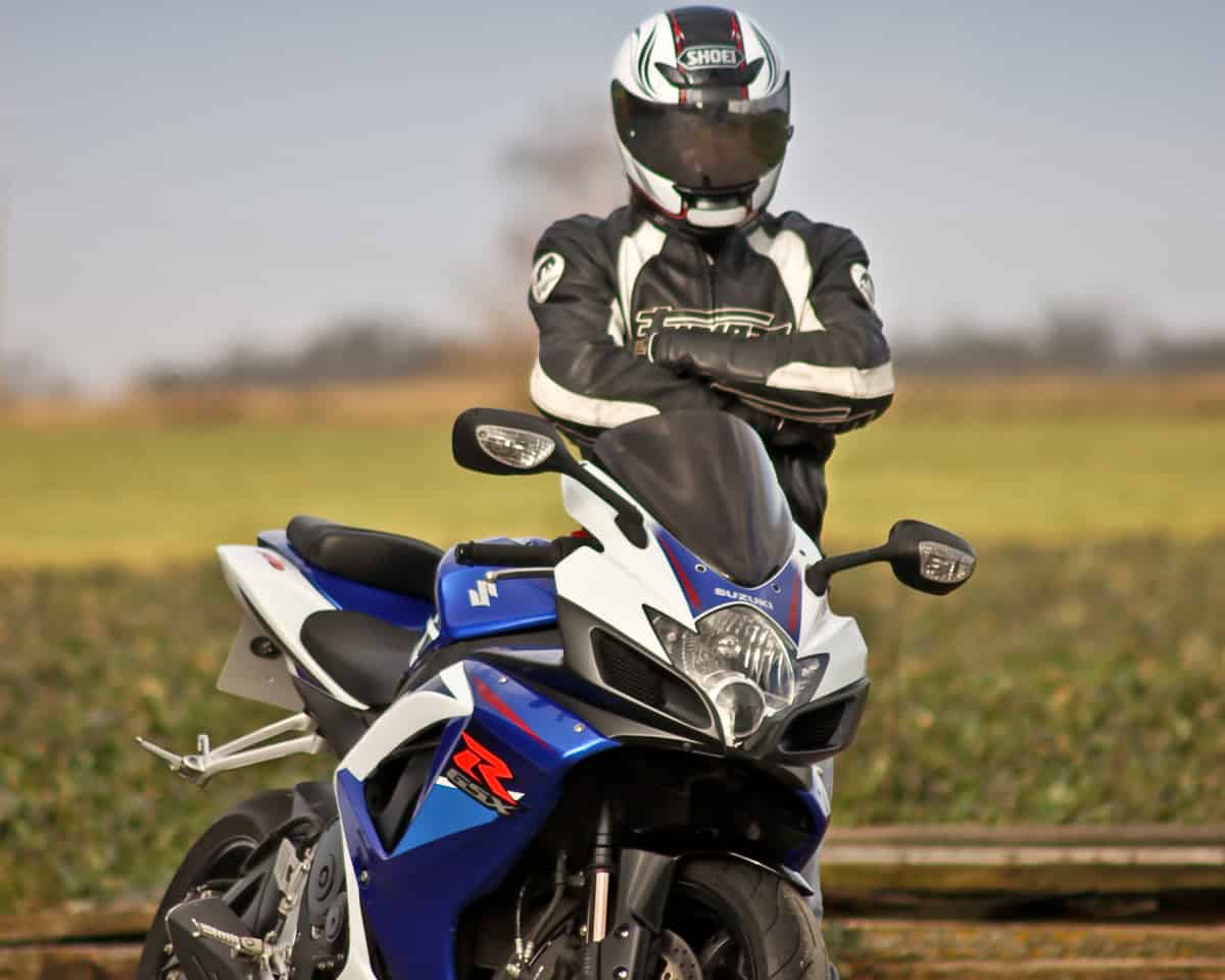 Homem parado ao lado de uma moto Suzuki GSX 750, nas cores azul e branca