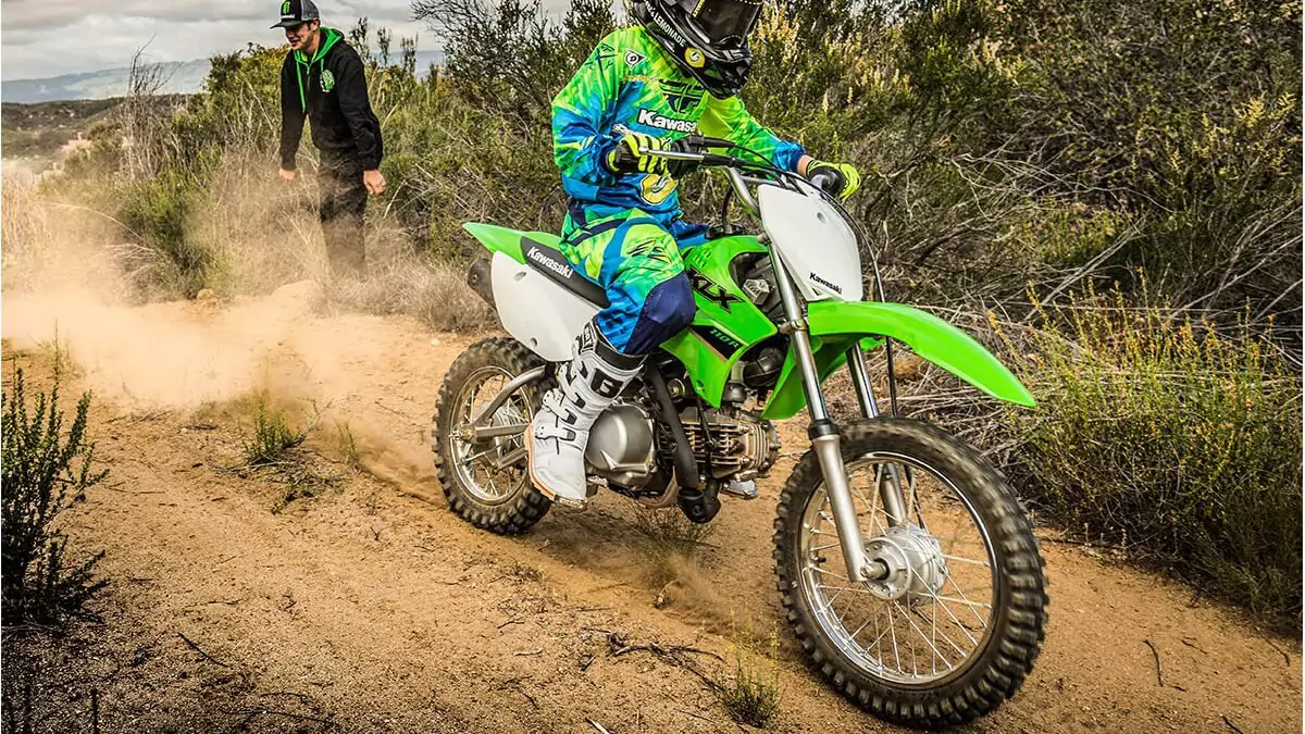 Homem pilotando motocicleta de trilha verde na estrada