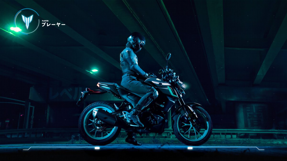 Mulher sentada encima de uma motocicleta Yamaha MT 125 2024, nas cores preta e azul, dentro de um estacionamento escuro