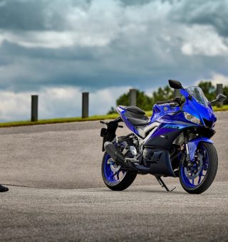 Mulher parada olhando uma moto Yamaha R3 azul