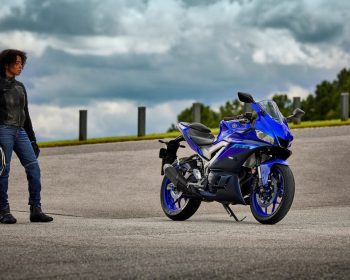 Mulher parada olhando uma moto Yamaha R3 azul